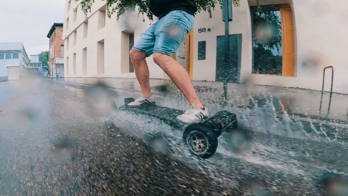 Rider salpicando por una calle mojada con un monopatín eléctrico ONSRA en una prueba bajo la lluvia